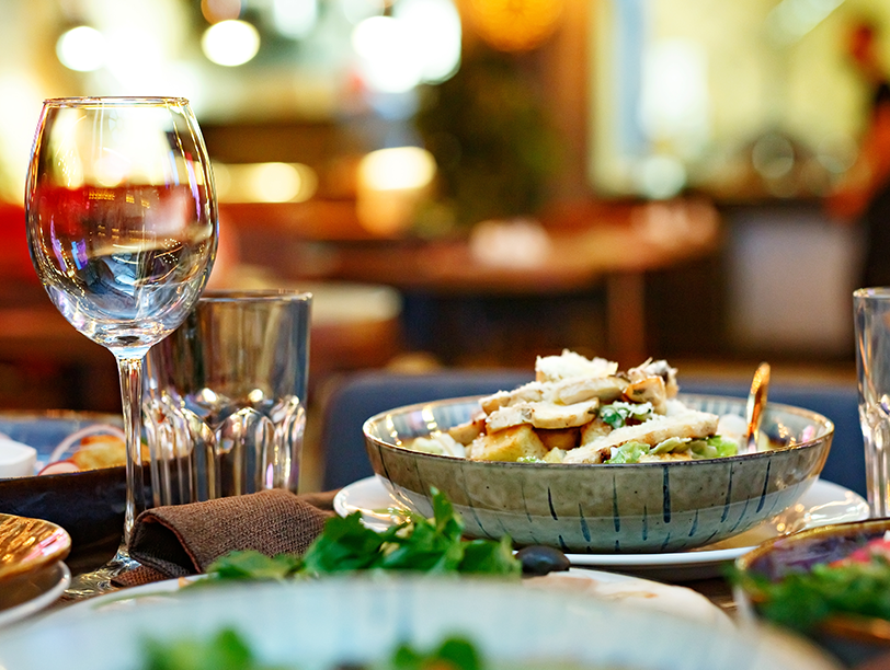 A photo of a table with plates of food and glasses of wine